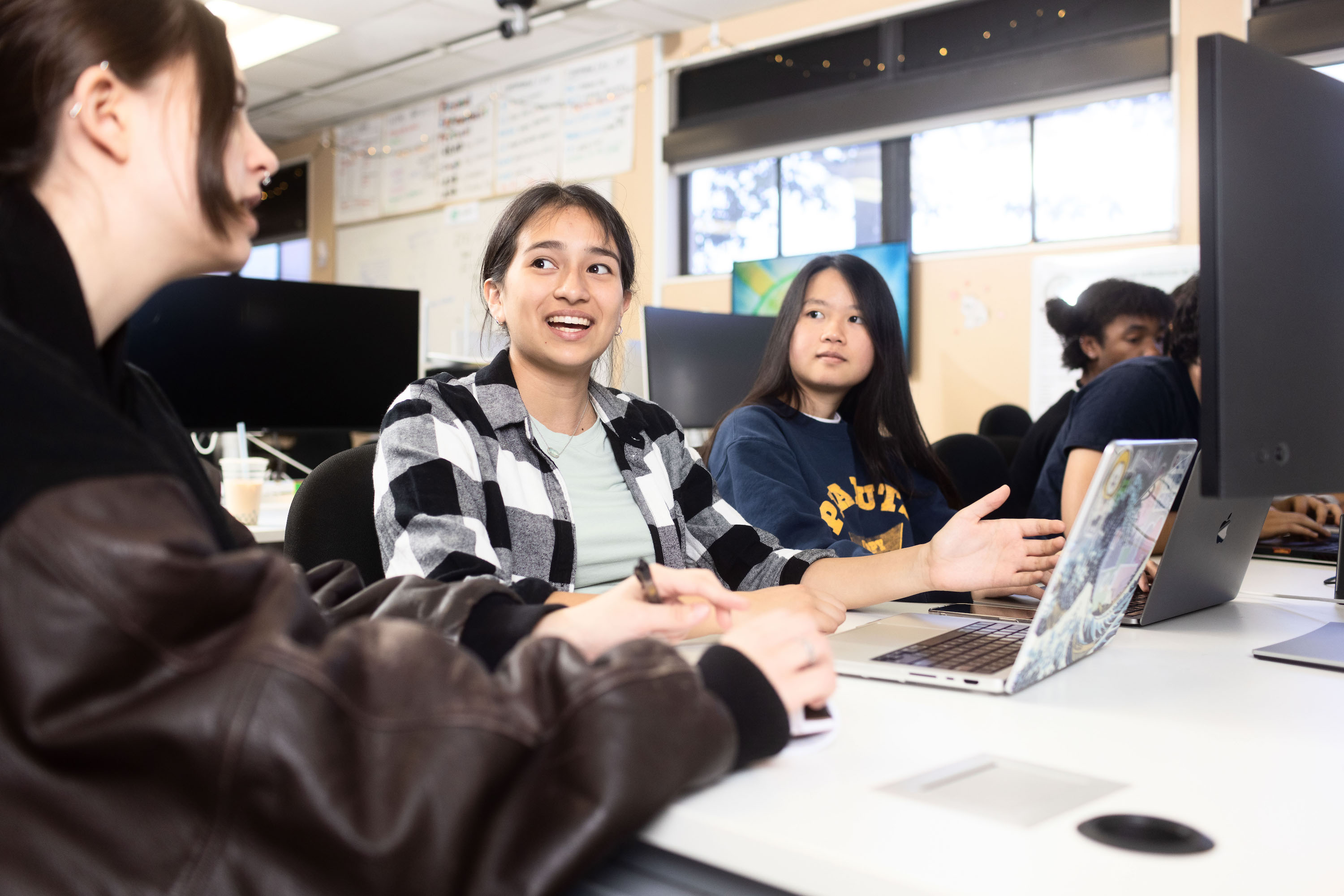 Photo shows three students discussing work together.