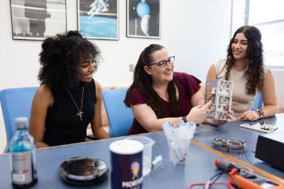 Photo of LMU Physics professor, Emily Hawkins, working with students in a lab.