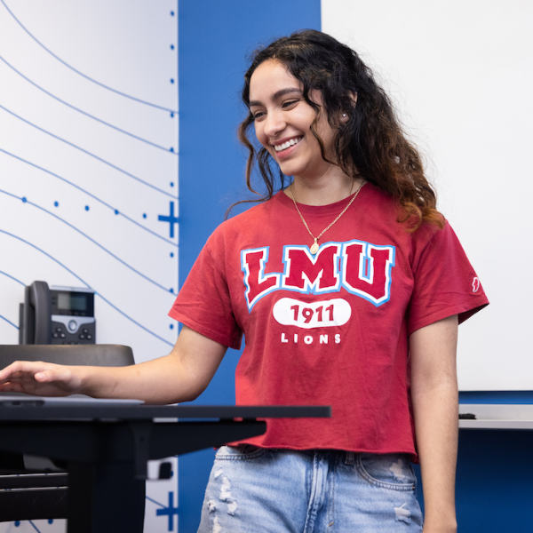 A student standing at a presentation podium in a classroom.