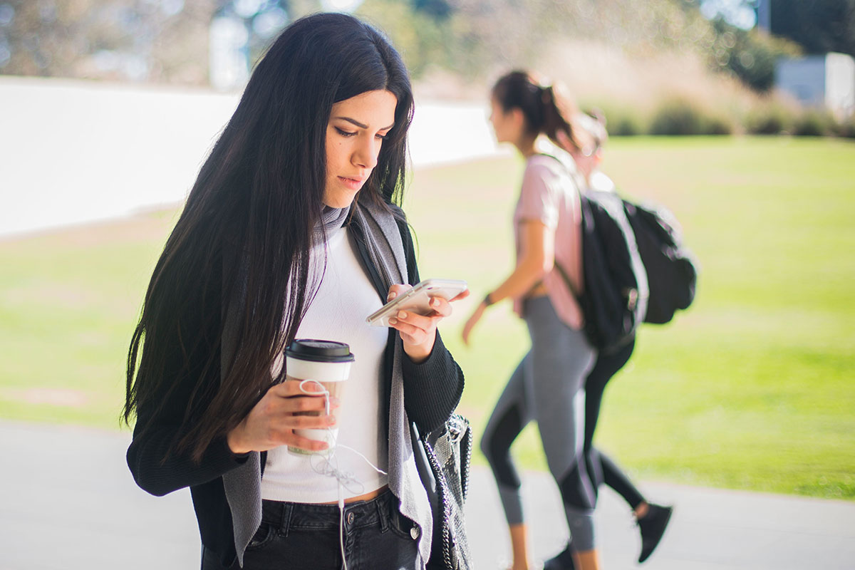 A student checking her phone outside the library